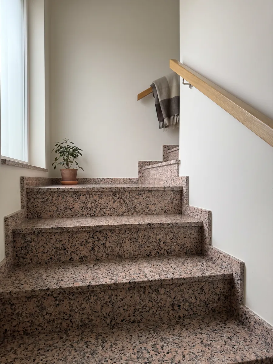 Escalera interior con peldaños de Granito Rosa Porriño con pasamanos: rosa salmón granulado con puntos negros