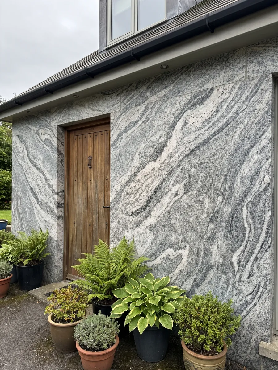 Fachada de casa revestida con Granito Verde Marina junto a una puerta de madera: bandas ondulantes blancas y grises de grano visible; en la foto no se aprecian tonos verdes