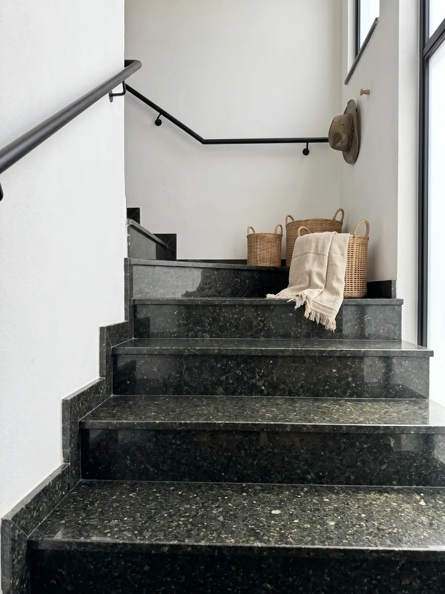 Escalera interior con peldaños de Granito Verde Ubatuba con pasamanos: verde casi negro con destellos de verde claro y dorado