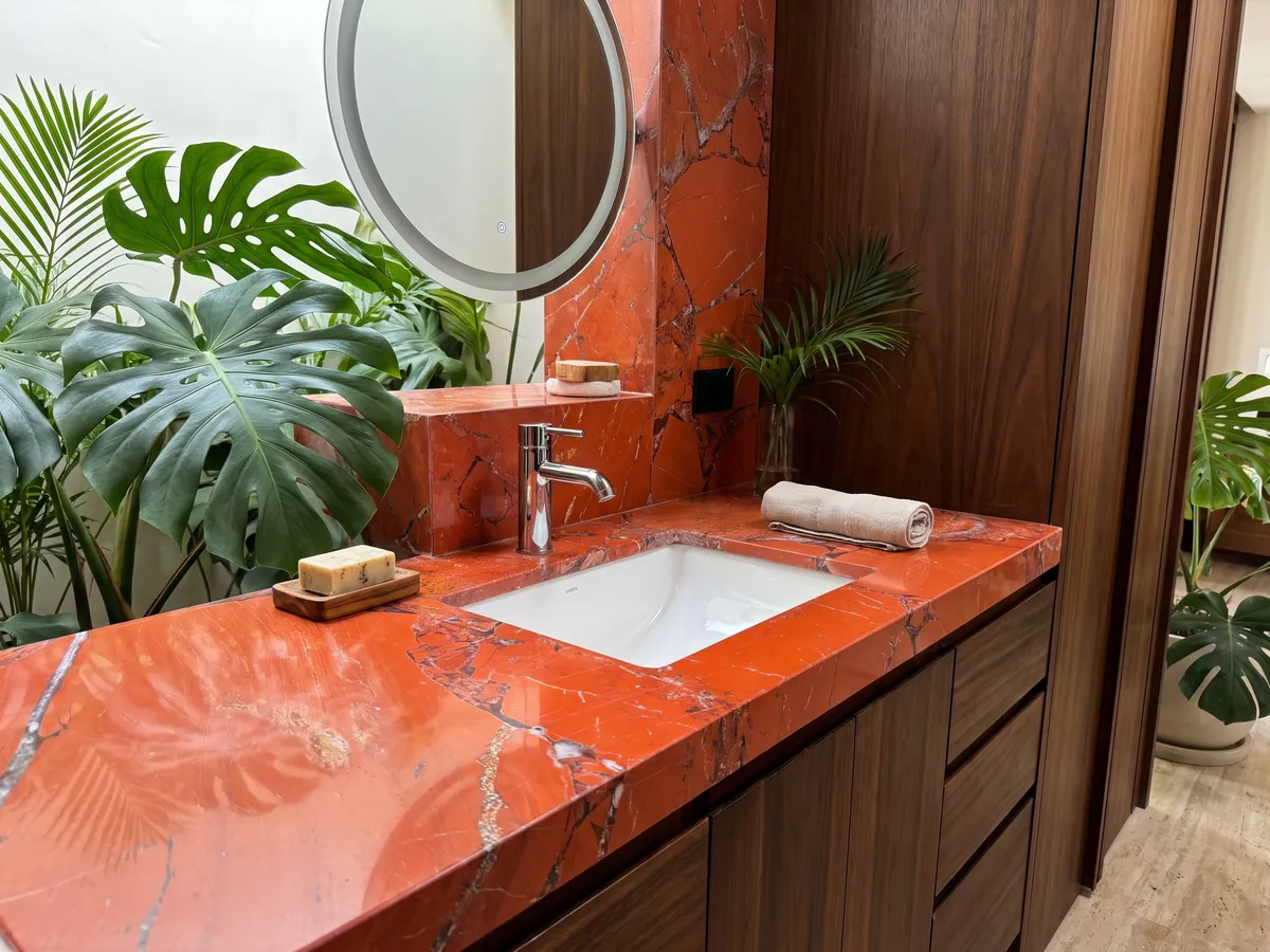Cubierta de lavabo y pared de baño en Jaspe Rojo con lavamanos blanco y grifería cromada: rojo anaranjado intenso en piezas grandes con juntas grises finas
