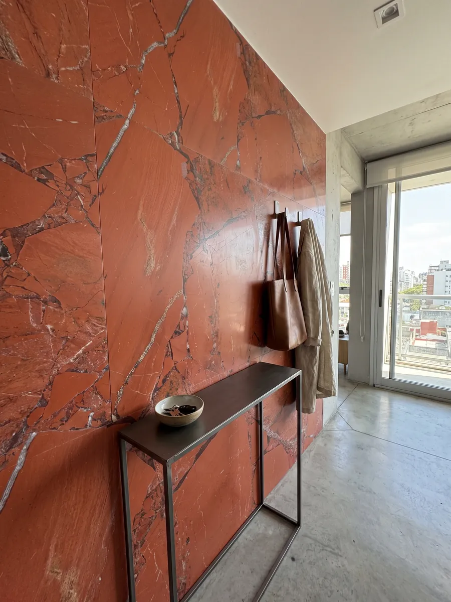 Pared de recibidor revestida con Jaspe Rojo con consola estrecha: rojo anaranjado intenso en piezas grandes con juntas grises finas