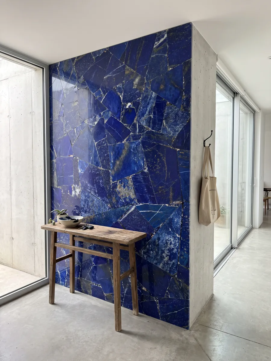 Pared de recibidor revestida con Lapislázuli con consola estrecha: azul ultramar intenso en piezas angulosas con motas blancas y doradas