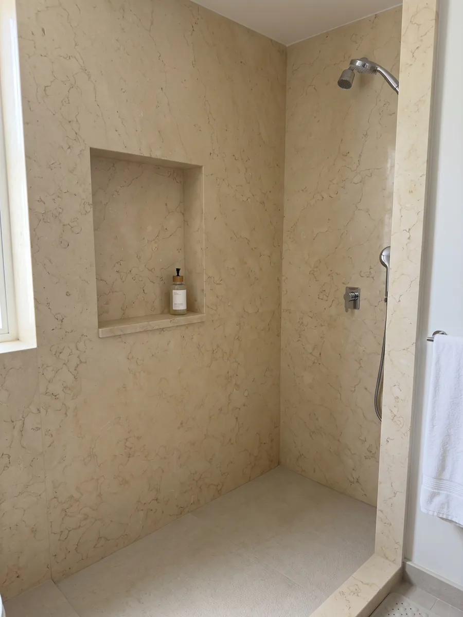 Ducha revestida con placas enteras de Mármol Amarillo Silvia Oro con nicho empotrado: amarillo pálido muy uniforme con un dibujo fino de líneas claras apenas visible
