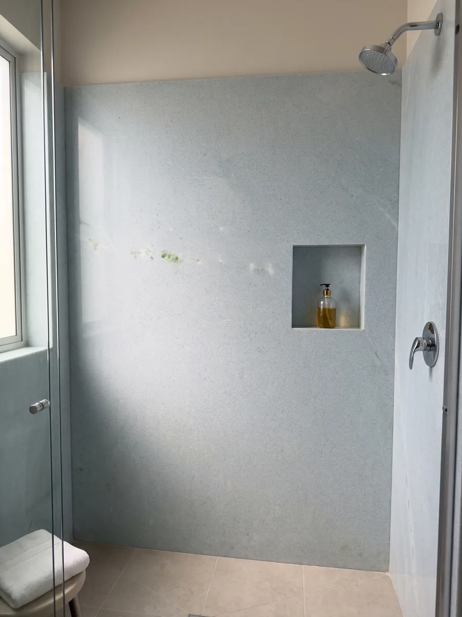 Ducha revestida con placas enteras de Mármol Azul Cielo con nicho empotrado: celeste pálido casi uniforme de grano fino, con una inclusión verde a la izquierda