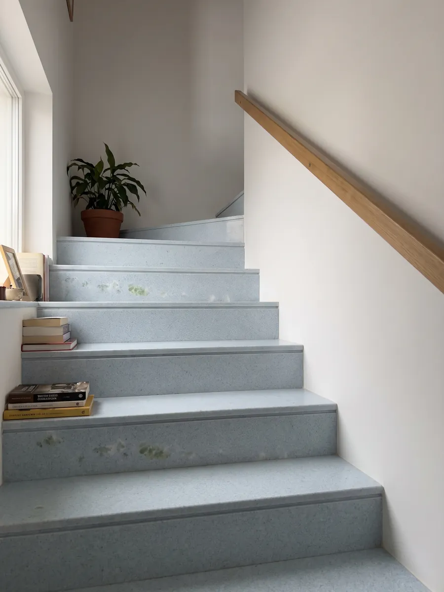 Escalera interior con peldaños de Mármol Azul Cielo con pasamanos: celeste pálido casi uniforme de grano fino, con una inclusión verde a la izquierda