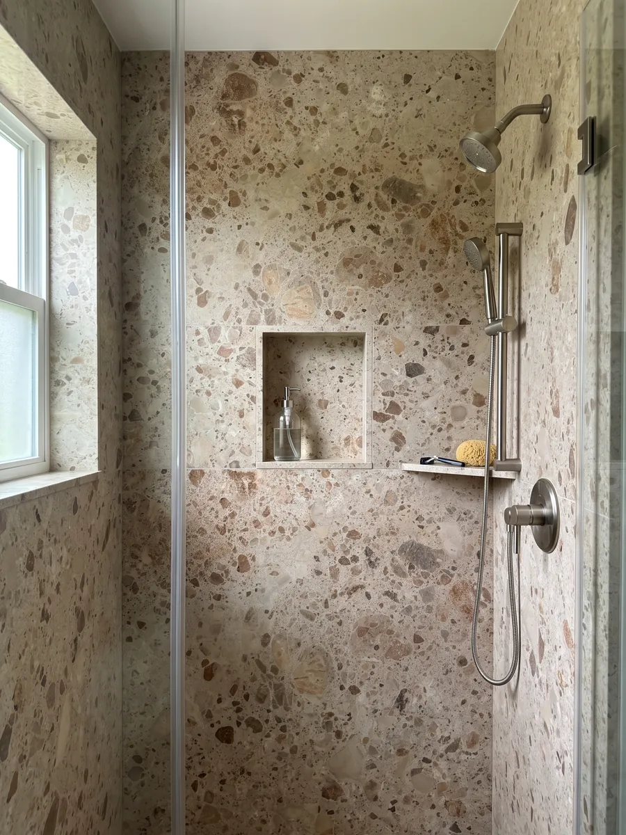 Ducha revestida con placas enteras de mármol beige Ambrosia con nicho empotrado: matriz beige con fragmentos redondeados marrones y óxido de varios tamaños