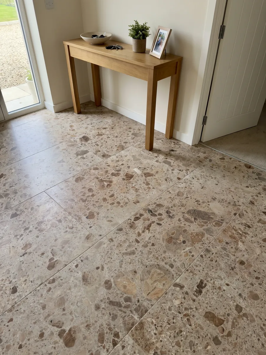 Piso de recibidor en placas grandes de mármol beige Ambrosia con luz natural: matriz beige con fragmentos redondeados marrones y óxido de varios tamaños