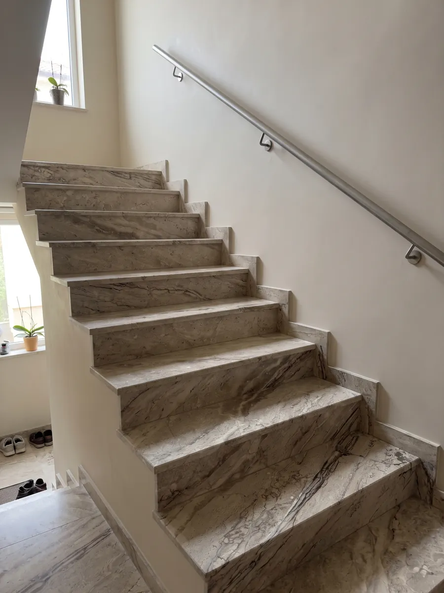 Escalera interior con peldaños de mármol beige Breccia Aurora con pasamanos: beige grisáceo con vetas paralelas marrones en diagonal y zona más rayada abajo