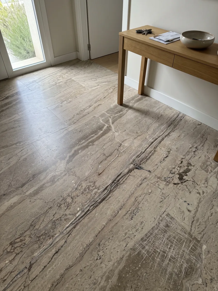 Piso de recibidor en placas grandes de mármol beige Breccia Aurora con luz natural: beige grisáceo con vetas paralelas marrones en diagonal y zona más rayada abajo