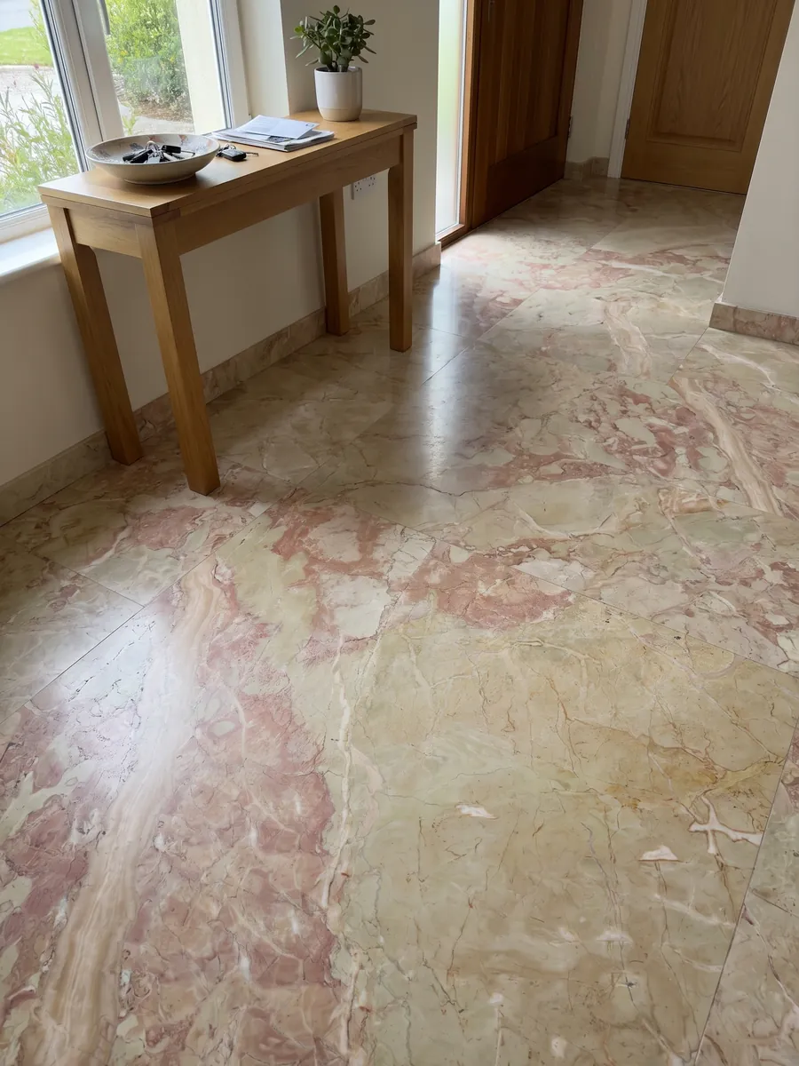 Piso de recibidor en placas grandes de mármol beige Breccia D’Aragona con luz natural: fragmentos beige verdosos grandes con manchas rosa coral en el borde izquierdo