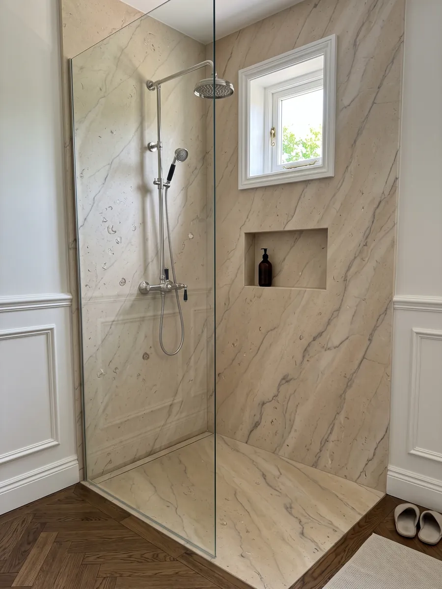 Ducha revestida con placas enteras de Mármol Beige Maya con nicho empotrado: beige cálido con vetas grises suaves y pequeños fósiles