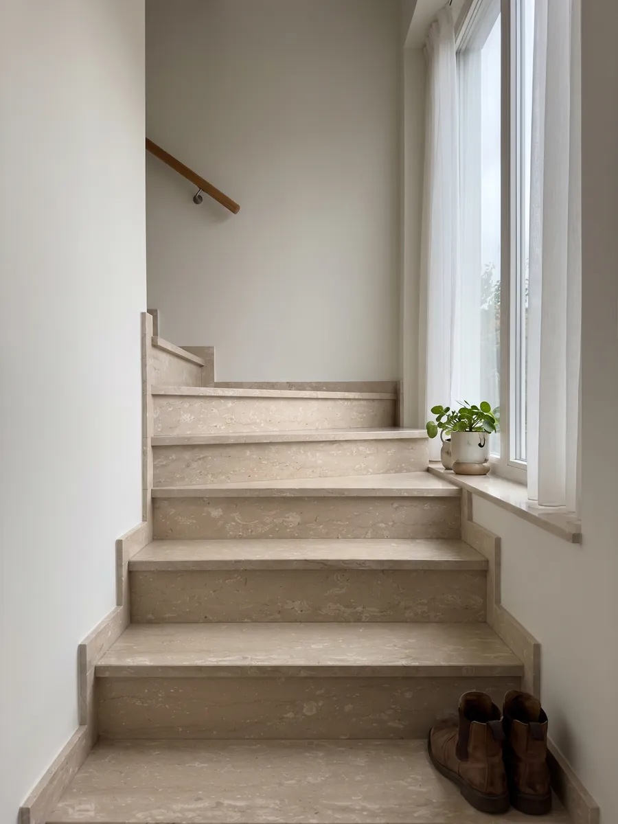 Escalera interior con peldaños de mármol beige Perlatino con pasamanos: beige con pequeñas manchas crema alineadas en sentido horizontal