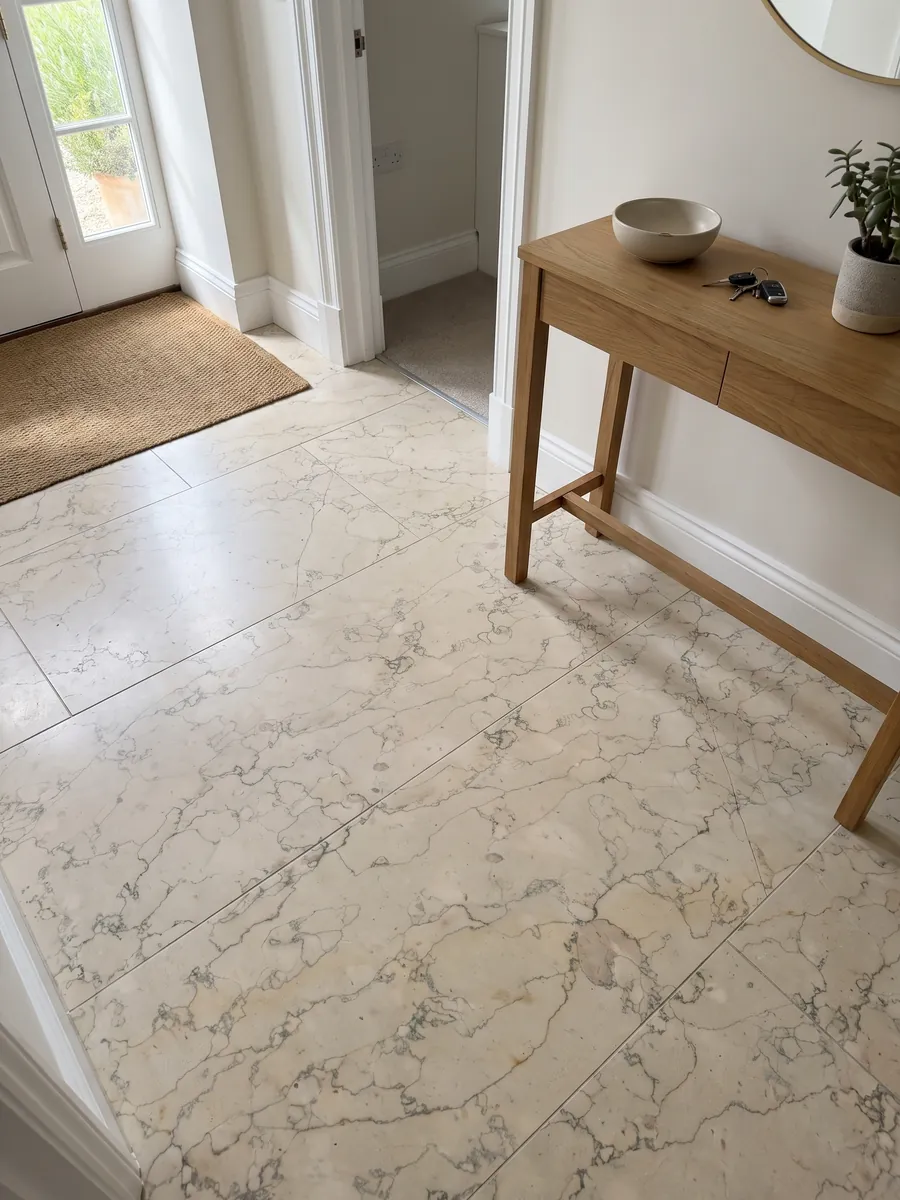Piso de recibidor en placas grandes de mármol beige Verdello con luz natural: fondo beige con una red fina de líneas grises sinuosas, como craquelado