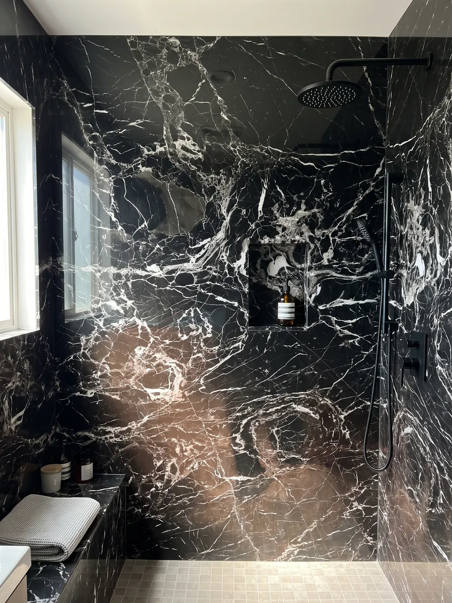 Ducha revestida con placas enteras de Mármol Black Rose con nicho empotrado: negro con red densa de vetas blancas y una zona inferior con matiz marrón