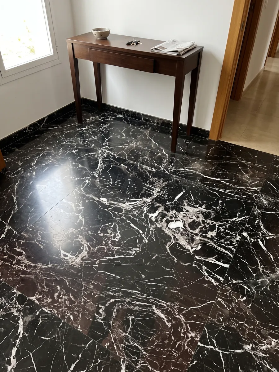 Piso de recibidor en placas grandes de Mármol Black Rose con luz natural: negro con red densa de vetas blancas y una zona inferior con matiz marrón