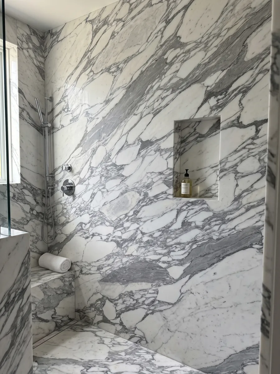 Ducha revestida con placas enteras de mármol blanco Arabesque con nicho empotrado: fragmentos blancos alargados envueltos en vetas grises gruesas en diagonal