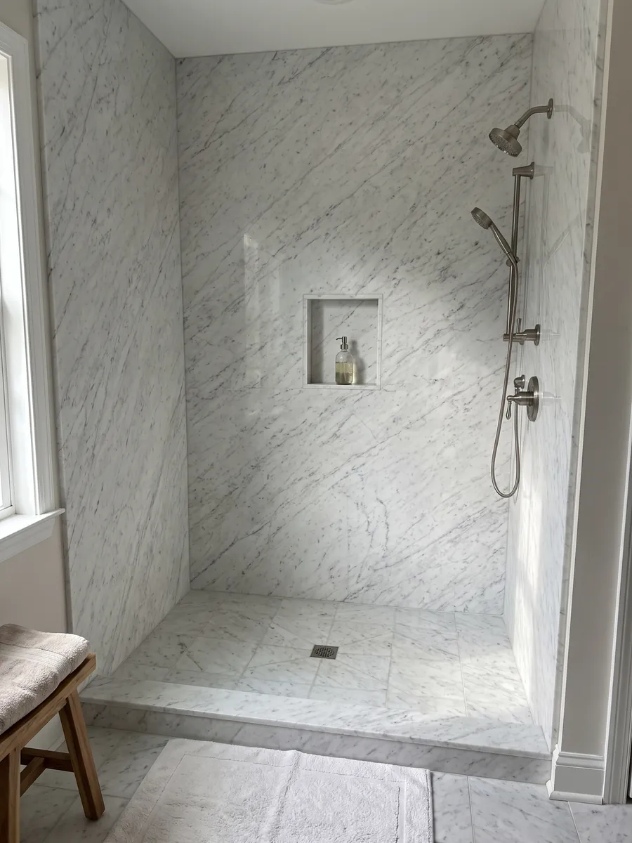 Ducha revestida con placas enteras de mármol blanco Bianco Carrara C Extra con nicho empotrado: blanco con vetas grises finas y suaves en diagonal sobre toda la placa