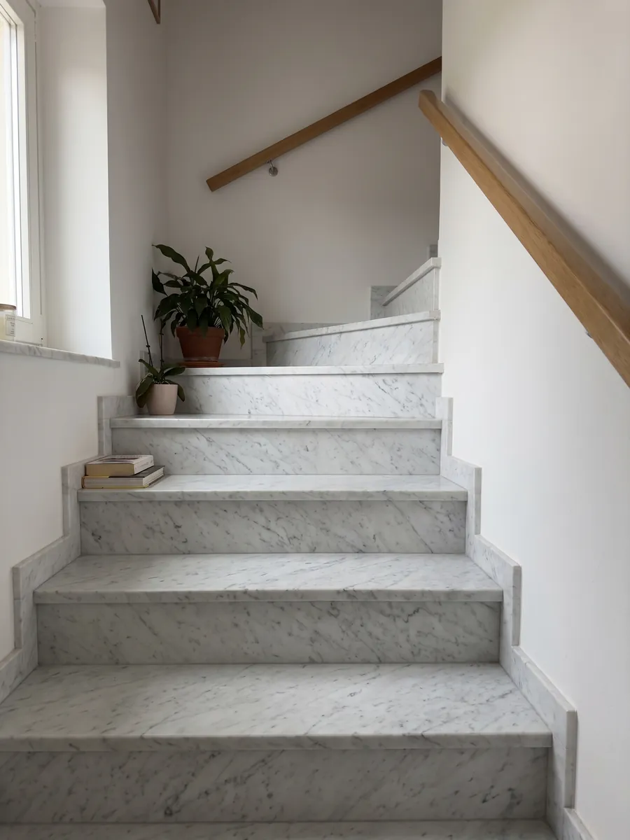 Escalera interior con peldaños de mármol blanco Bianco Carrara C Extra con pasamanos: blanco con vetas grises finas y suaves en diagonal sobre toda la placa