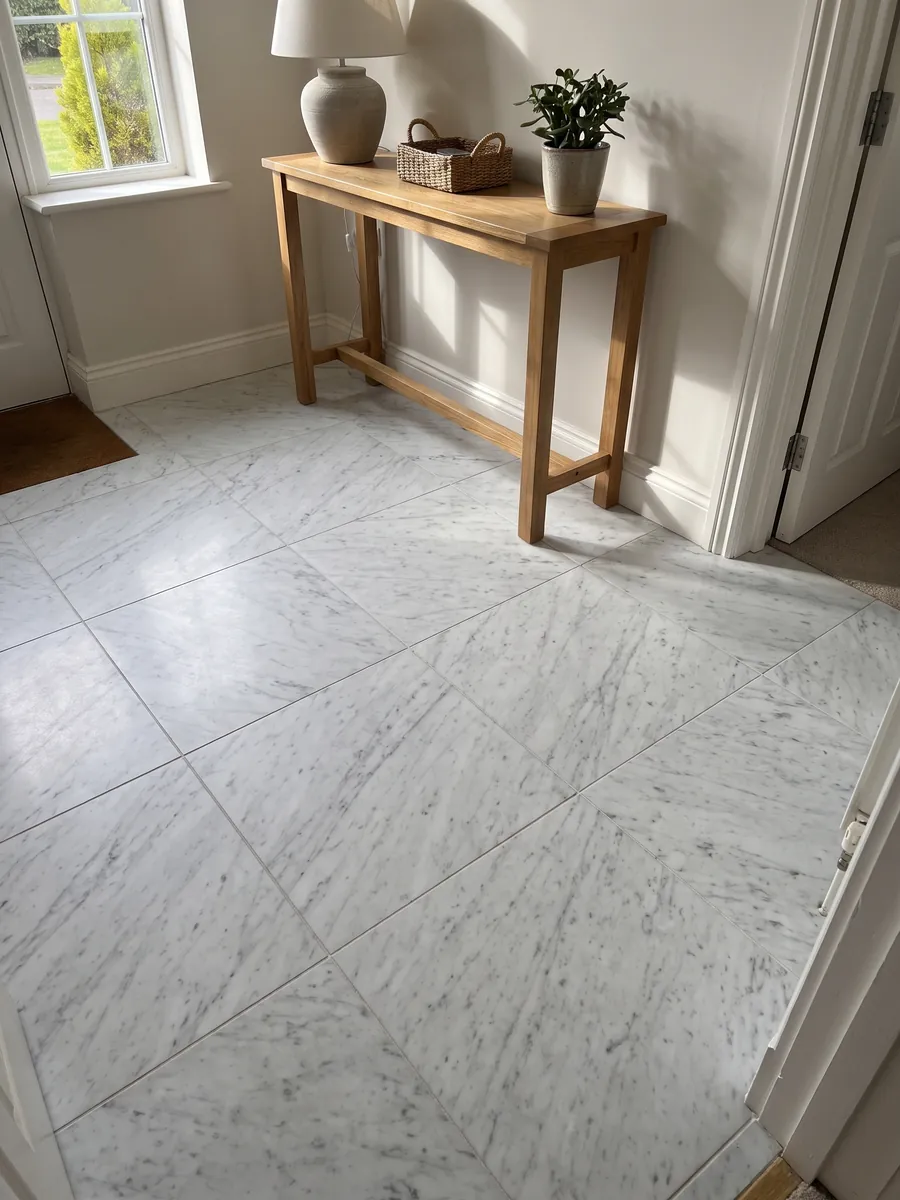 Piso de recibidor en placas grandes de mármol blanco Bianco Carrara C Extra con luz natural: blanco con vetas grises finas y suaves en diagonal sobre toda la placa