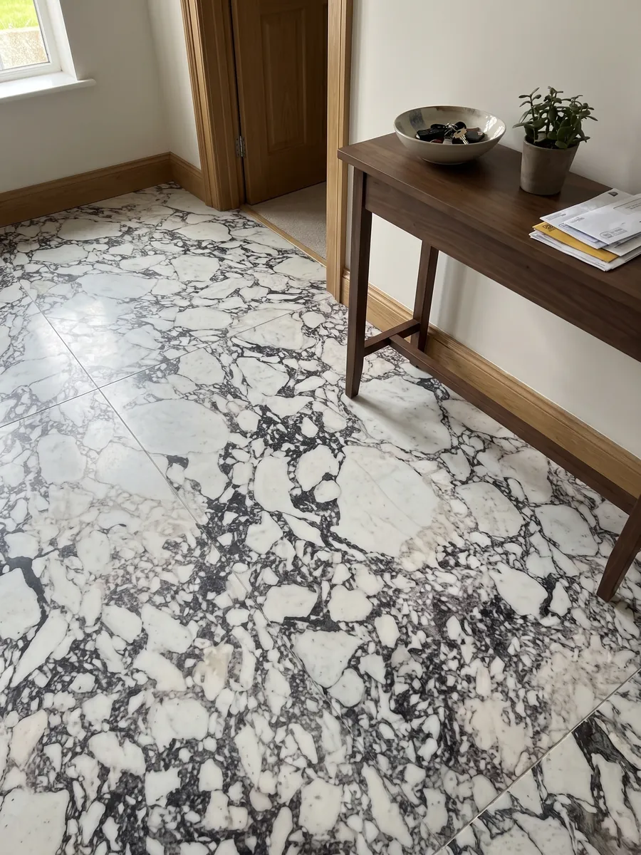 Piso de recibidor en placas grandes de mármol blanco Breccia Capraia con luz natural: fragmentos blancos rodeados de una red densa gris oscura con matices violáceos