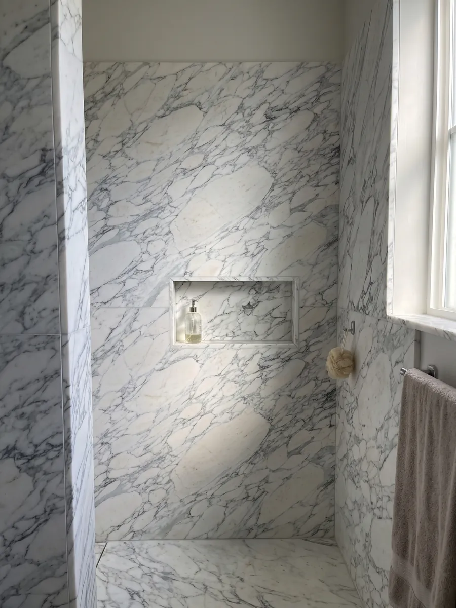 Ducha revestida con placas enteras de mármol blanco Breccia di Serravezza con nicho empotrado: fragmentos blancos con red fina gris azulada repartida por toda la placa