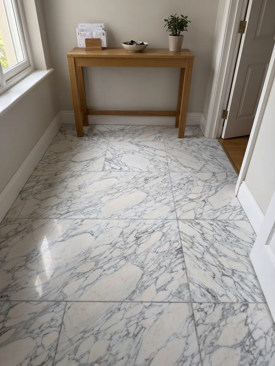 Piso de recibidor en placas grandes de mármol blanco Breccia di Serravezza con luz natural: fragmentos blancos con red fina gris azulada repartida por toda la placa