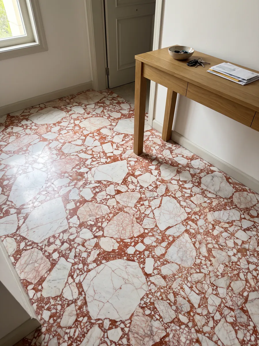 Piso de recibidor en placas grandes de mármol blanco Calacatta Antique con luz natural: fragmentos blancos angulosos unidos por una matriz roja coral intensa