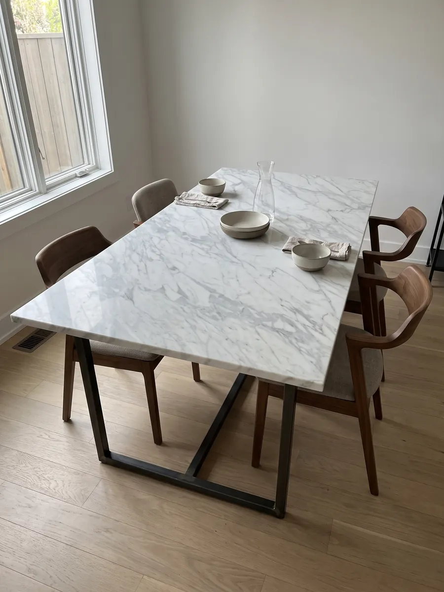 Mesa de comedor con cubierta de mármol blanco Calacatta Classic sobre base de acero: blanco con vetas gris claro finas en diagonal sobre toda la placa