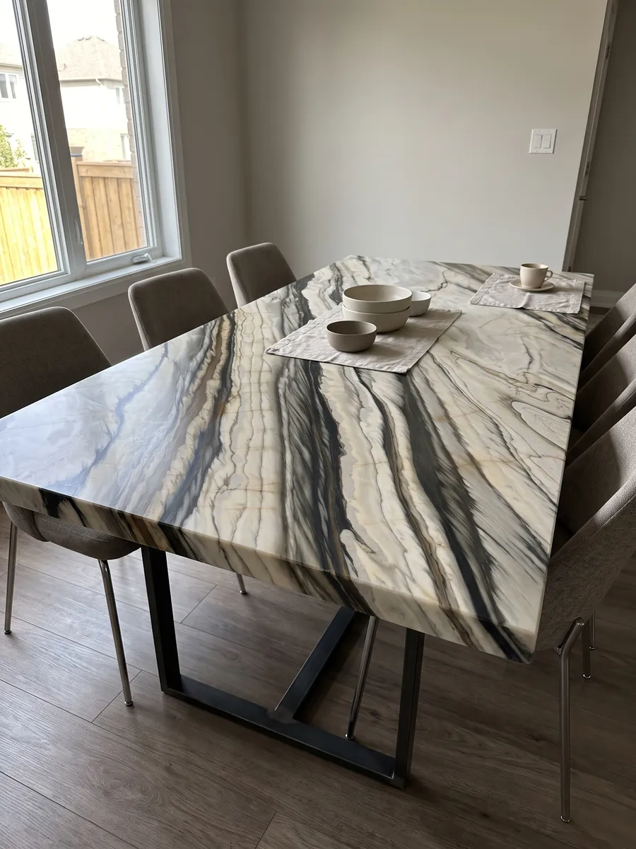 Mesa de comedor con cubierta de mármol blanco Calacatta Oyster sobre base de acero: bandas anchas negras y marrones paralelas en diagonal sobre crema