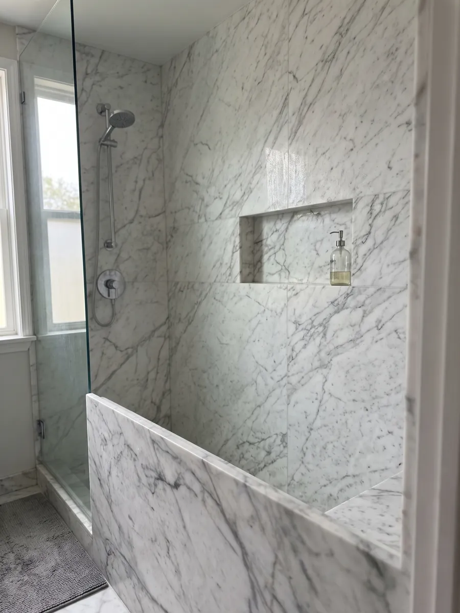Ducha revestida con placas enteras de mármol blanco Calacatta Vagli con nicho empotrado: blanco con vetas grises finas en red irregular
