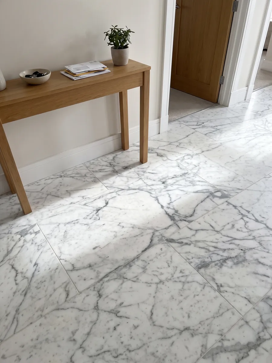 Piso de recibidor en placas grandes de mármol blanco Calacatta Vagli con luz natural: blanco con vetas grises finas en red irregular