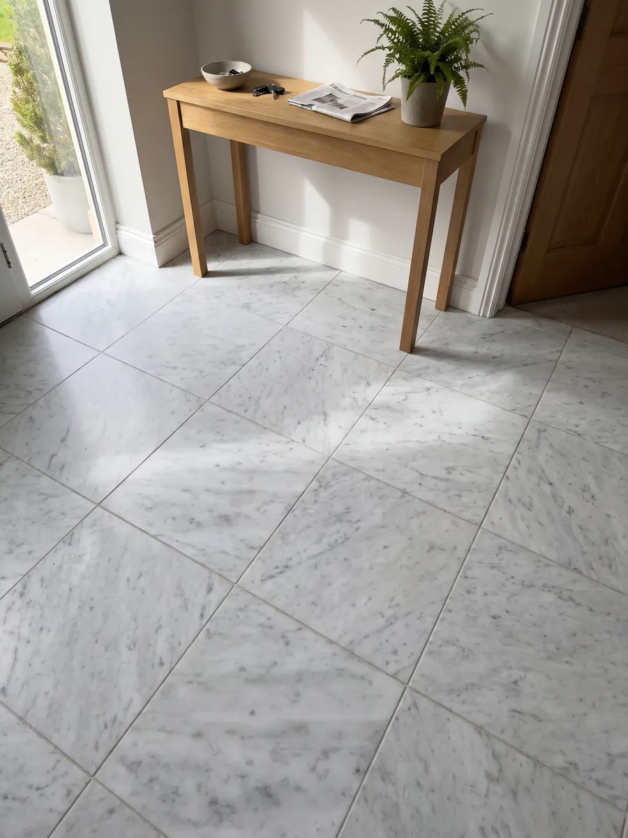 Piso de recibidor en placas grandes de mármol blanco Carrara CD con luz natural: blanco grisáceo con manchas grises difusas en diagonal