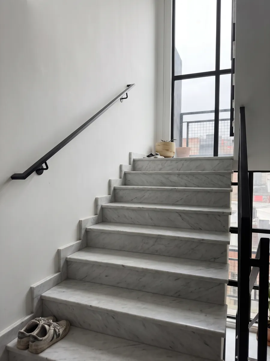 Escalera interior con peldaños de mármol blanco Dolomita con pasamanos: blanco grisáceo con vetas grises finas y alguna línea más oscura