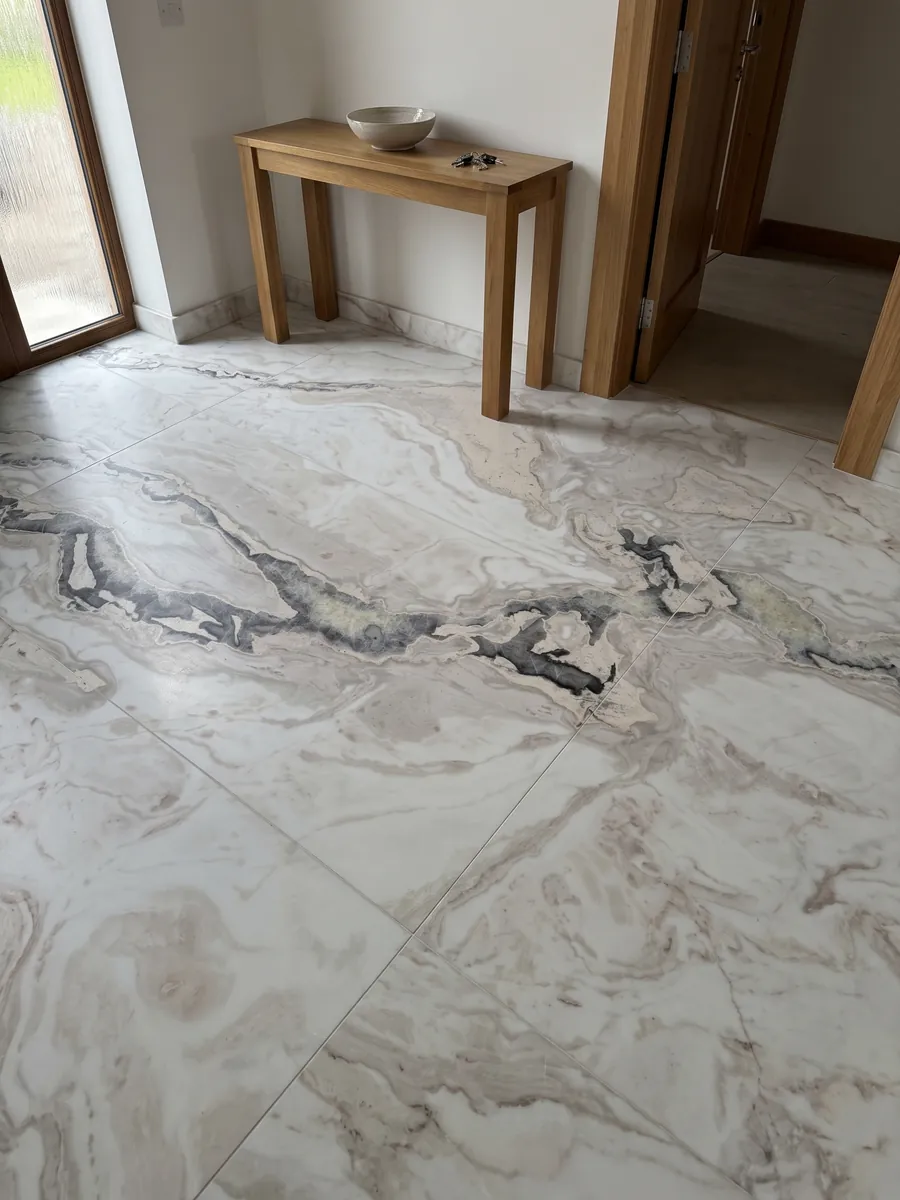 Piso de recibidor en placas grandes de mármol blanco Dover White con luz natural: blanco con una veta gris oscura irregular que cruza la parte superior