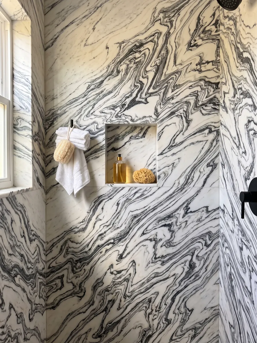 Ducha revestida con placas enteras de mármol blanco Fantastico Arni con nicho empotrado: vetas negras plegadas en zigzag que forman ondas continuas sobre fondo blanco