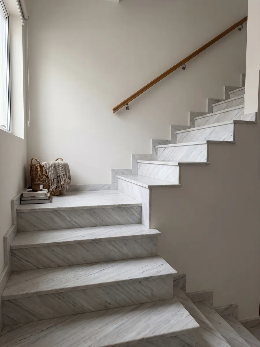 Escalera interior con peldaños de mármol blanco Palissandro con pasamanos: blanco grisáceo con trazos grises finos y paralelos en diagonal