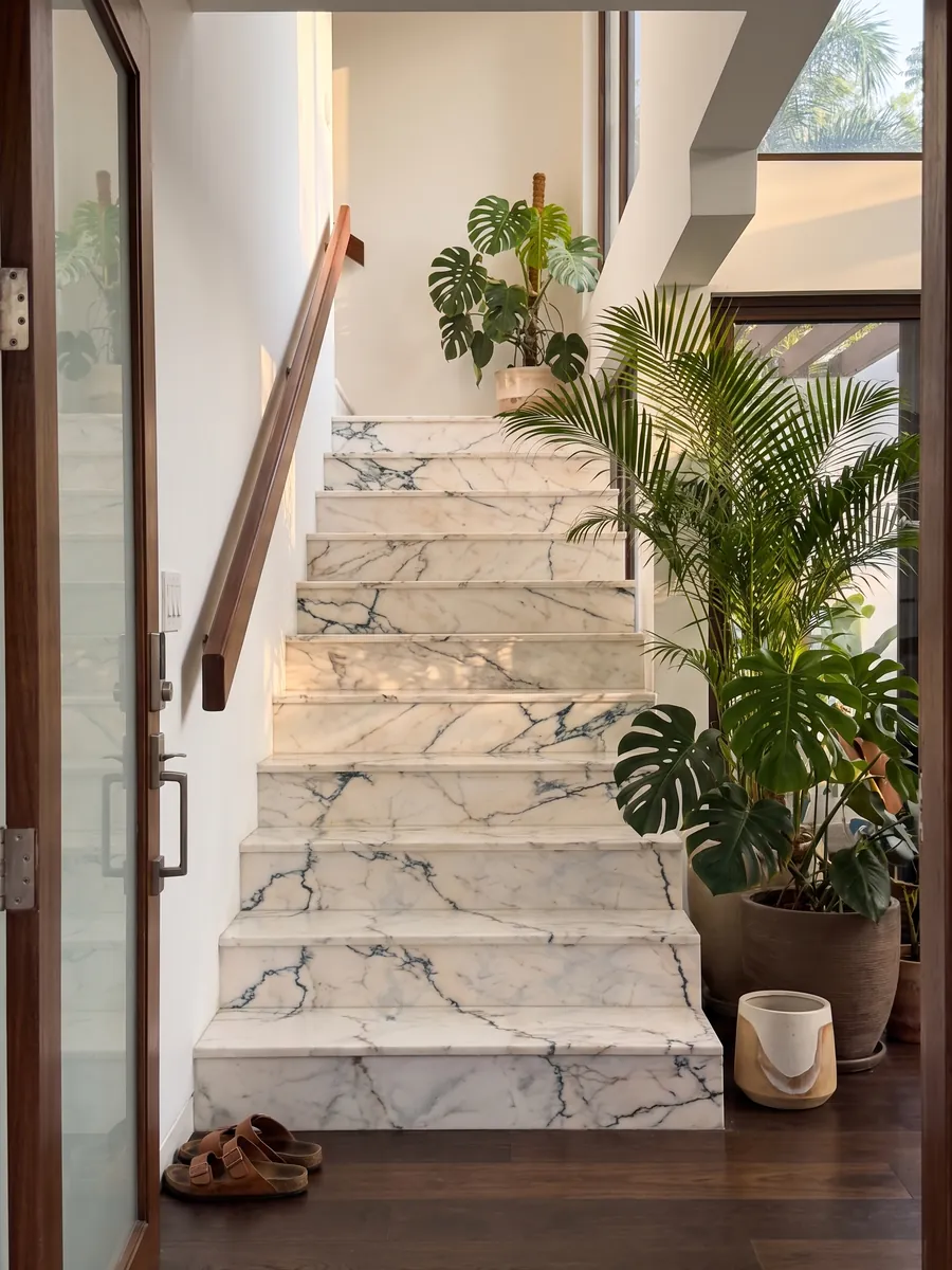 Escalera interior con peldaños de mármol blanco Paonazzo con pasamanos: blanco cálido con vetas finas verde azulado oscuro que parecen grietas
