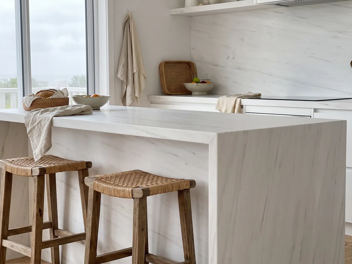 Isla de cocina con cubierta de mármol blanco Snow White y canto recto en una cocina con luz natural: blanco muy limpio con trazos grises apenas perceptibles en diagonal