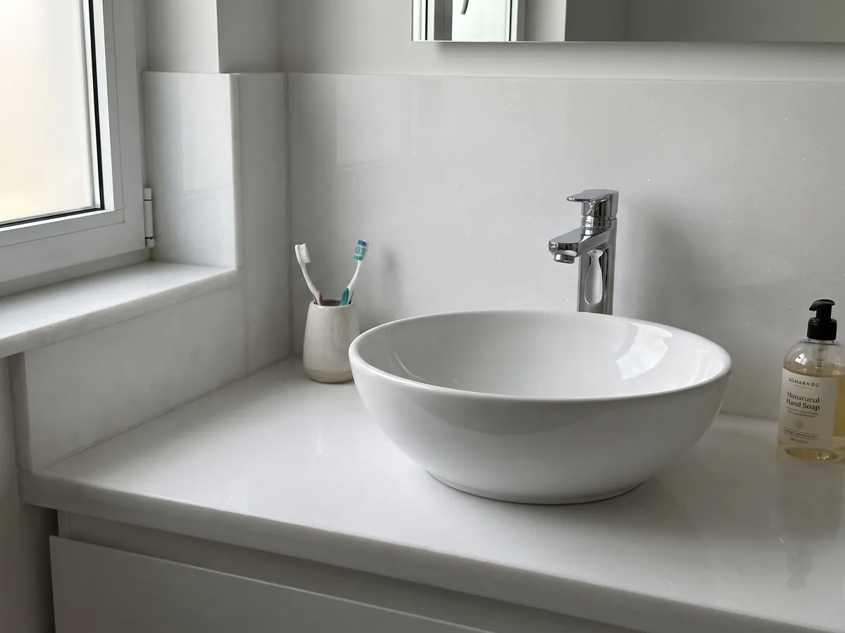 Cubierta de lavabo y pared de baño en mármol blanco Thassos con lavamanos blanco y grifería cromada: blanco puro uniforme sin dibujo apreciable