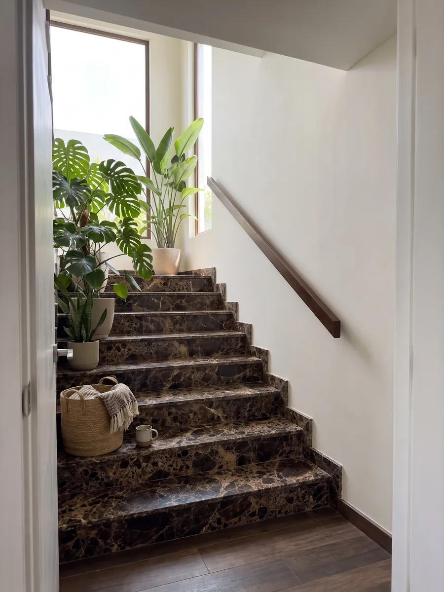 Escalera interior con peldaños de mármol café Emperador Oscuro con pasamanos: manchas marrón oscuro casi negras unidas por una red densa beige
