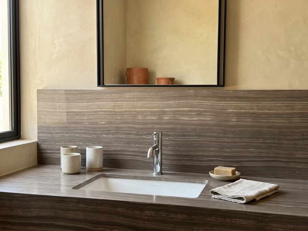 Cubierta de lavabo y pared de baño en mármol café Eramosa con lavamanos blanco y grifería cromada: marrón grisáceo con líneas finas horizontales paralelas tipo madera