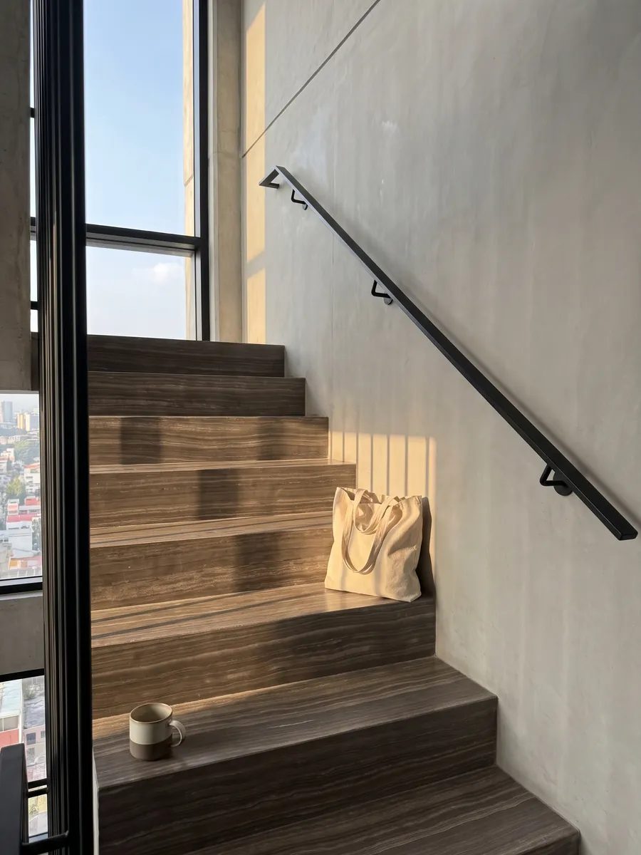 Escalera interior con peldaños de mármol café Eramosa con pasamanos: marrón grisáceo con líneas finas horizontales paralelas tipo madera