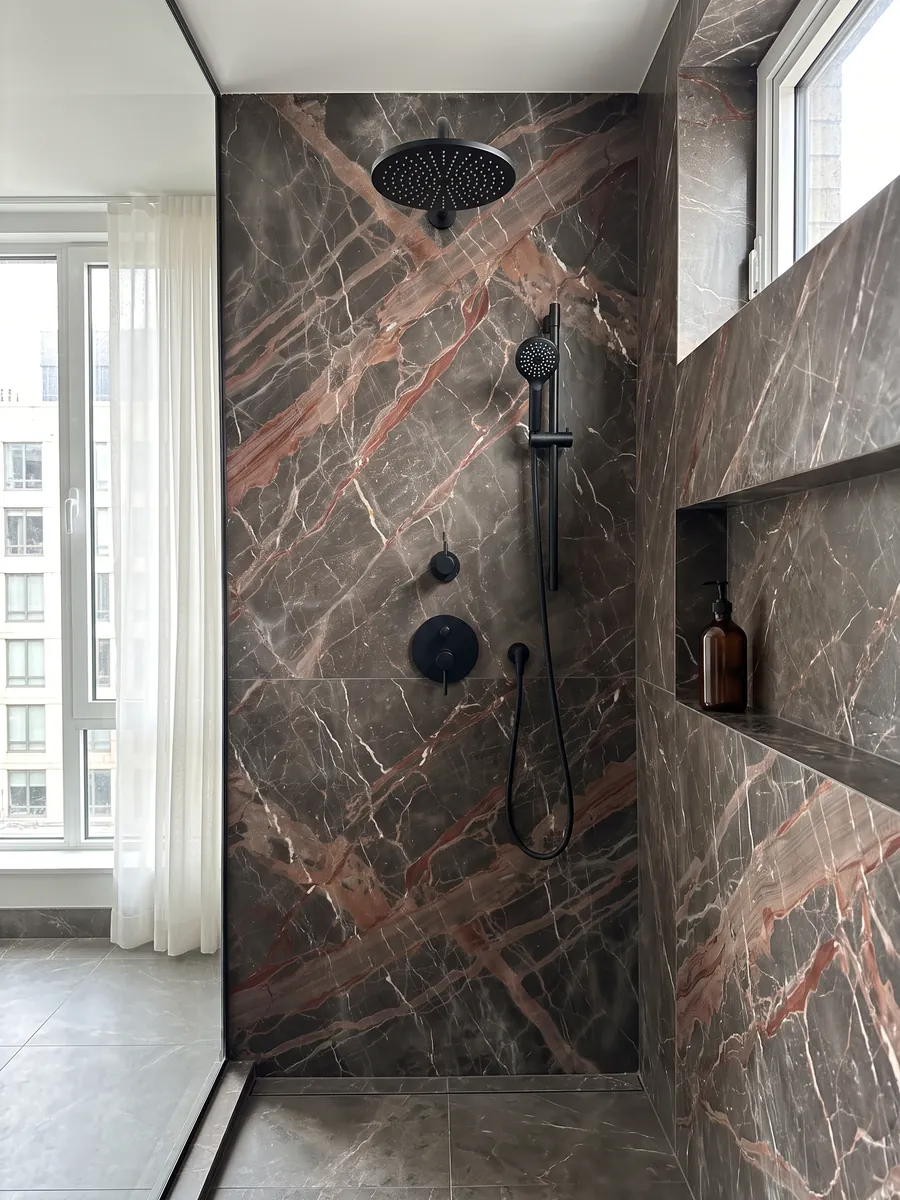 Ducha revestida con placas enteras de mármol café Ombra di Caravaggio con nicho empotrado: gris pardo oscuro cruzado por vetas terracota anchas y vetas blancas finas