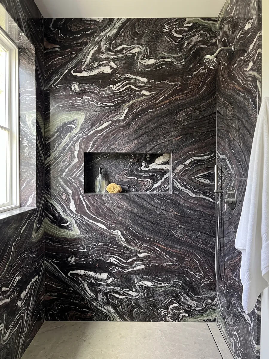 Ducha revestida con placas enteras de Mármol Cipollino Ondulato con nicho empotrado: fondo morado oscuro con vetas blancas muy onduladas y plegadas