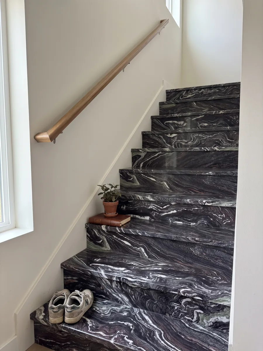 Escalera interior con peldaños de Mármol Cipollino Ondulato con pasamanos: fondo morado oscuro con vetas blancas muy onduladas y plegadas
