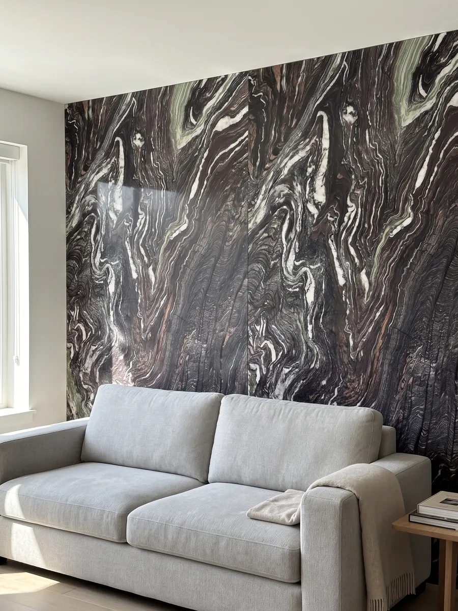 Pared de sala revestida con placas de Mármol Cipollino Ondulato abiertas en libro detrás de un sofá: fondo morado oscuro con vetas blancas muy onduladas y plegadas
