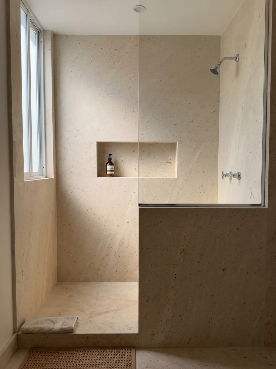 Ducha revestida con placas enteras de Mármol Fior di Crema con nicho empotrado: superficie crema muy pareja, de grano fino y sin vetas visibles