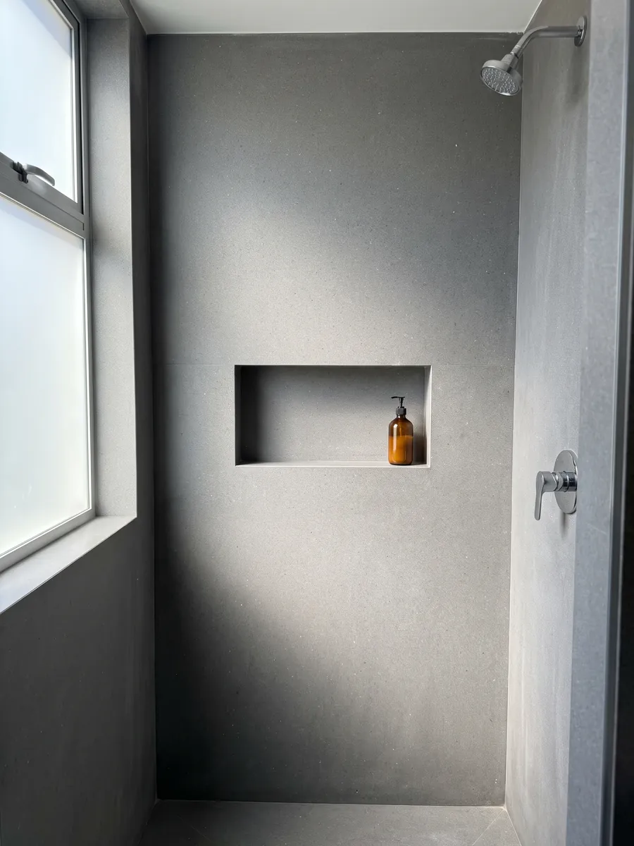 Ducha revestida con placas enteras de Mármol Gris Aitos con nicho empotrado: gris medio de grano fino y salpicado parejo, sin vetas