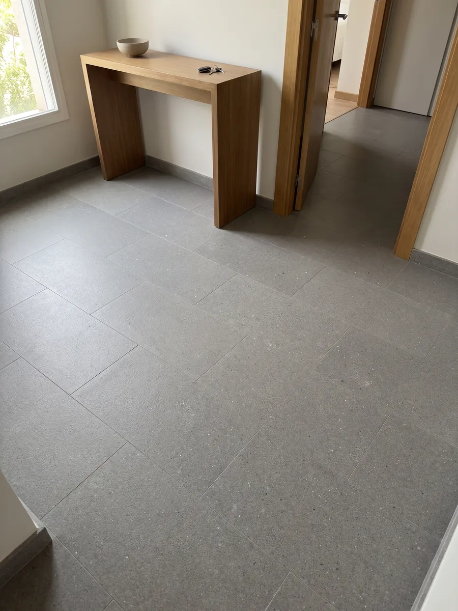 Piso de recibidor en placas grandes de Mármol Gris Aitos con luz natural: gris medio de grano fino y salpicado parejo, sin vetas