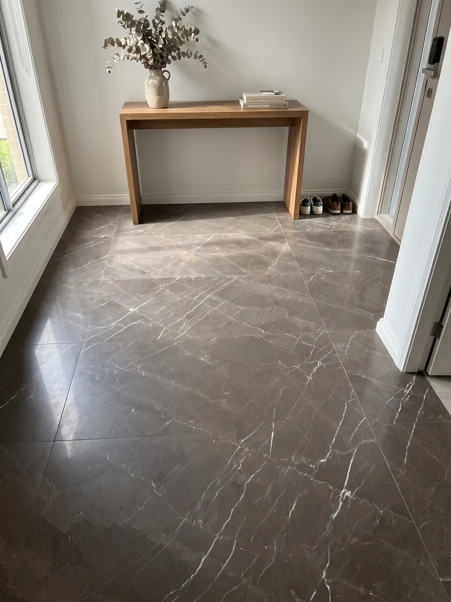 Piso de recibidor en placas grandes de Mármol Gris Amani con luz natural: fondo topo oscuro cruzado por vetas blancas finas en diagonal